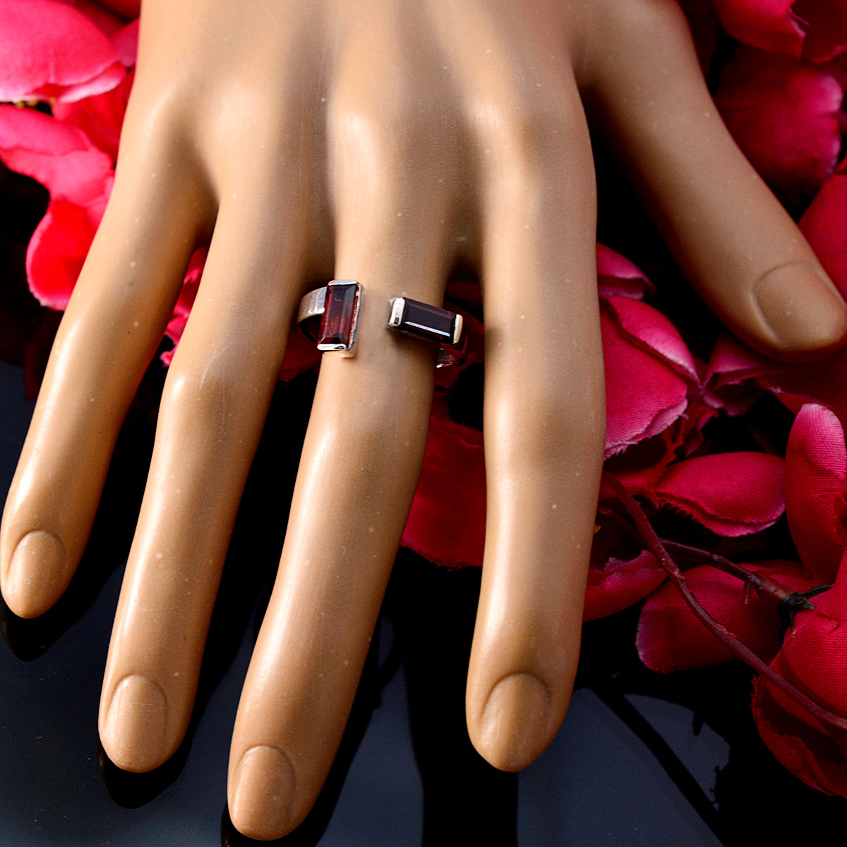 Hua red gemstone toi et moi ring with rectangular stones on hand display against red petals