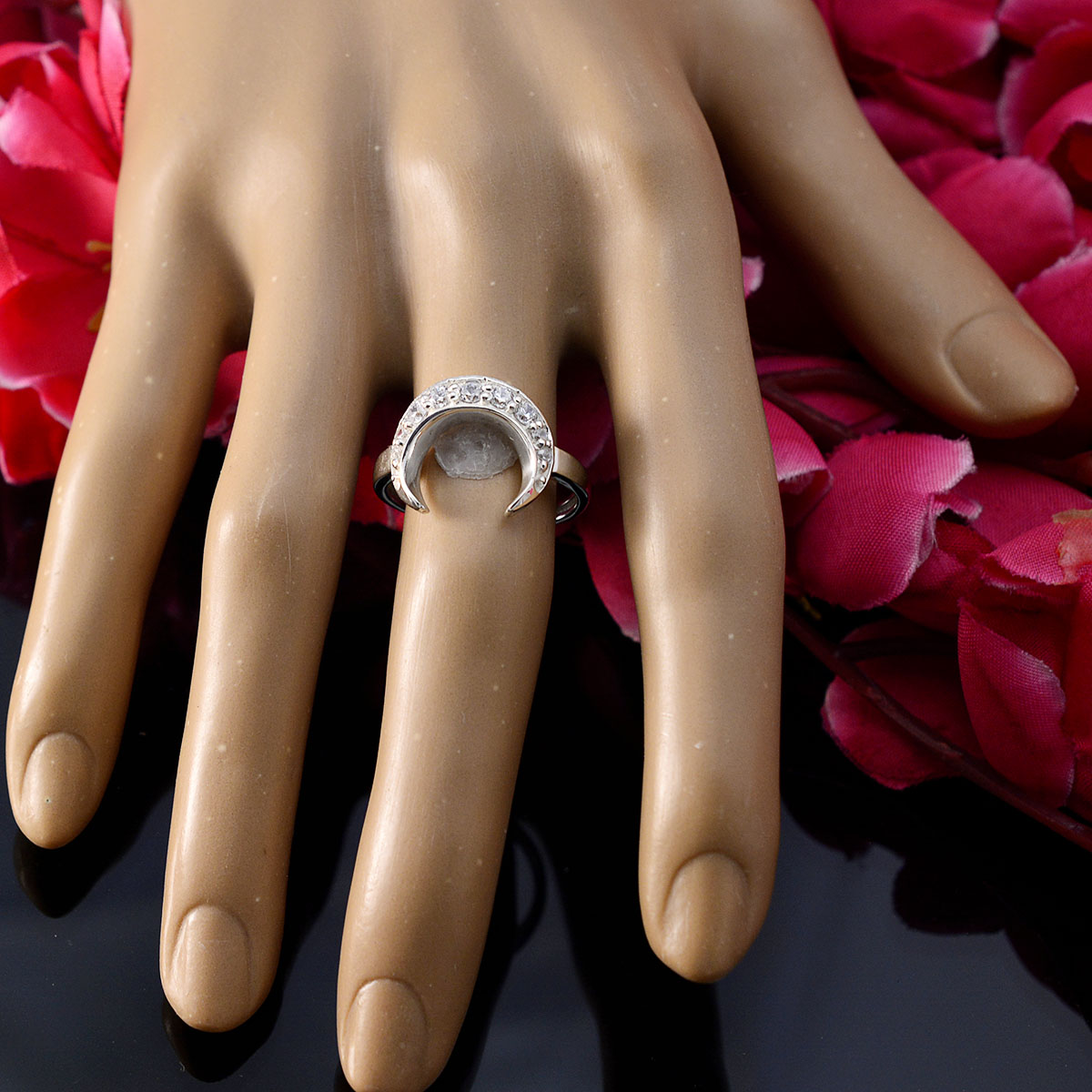 Liyana white gemstone ring for women featuring a crescent moon design on finger with pink flowers background