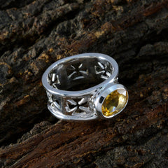 Emily yellow gemstone solitaire ring with silver cross cutout band on textured wood background