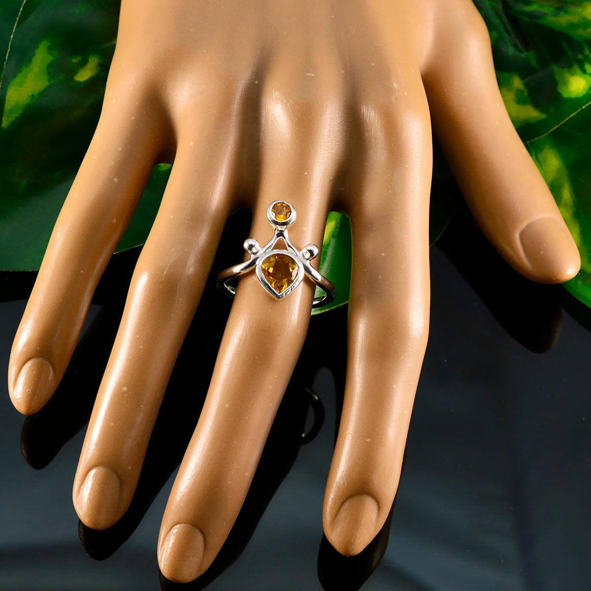 Rosa yellow gemstone toi et moi ring with silver band on mannequin hand against green background