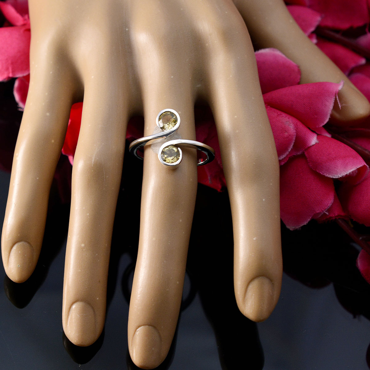 Laura yellow toi et moi ring silver bypass band with two yellow gemstones on display hand with pink petals