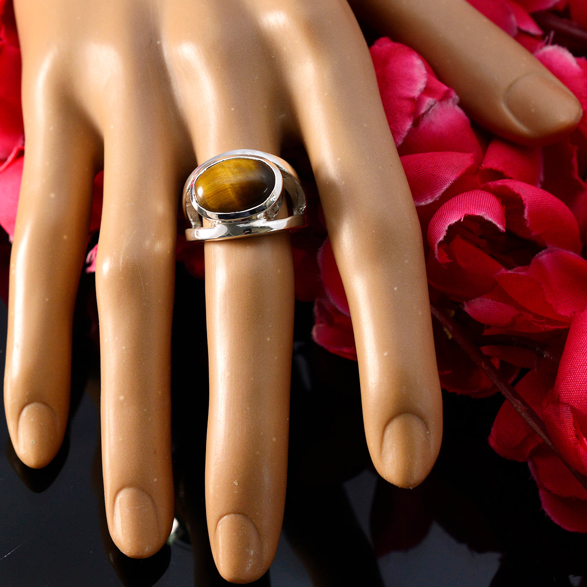 Eva artisan brown solitaire ring with polished band on mannequin hand against red flowers