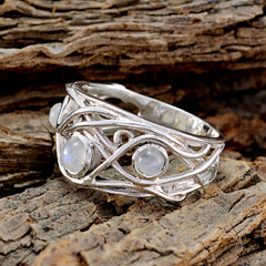 Laura white trilogy ring with intricate silver band and three round moonstone gems on textured wood
