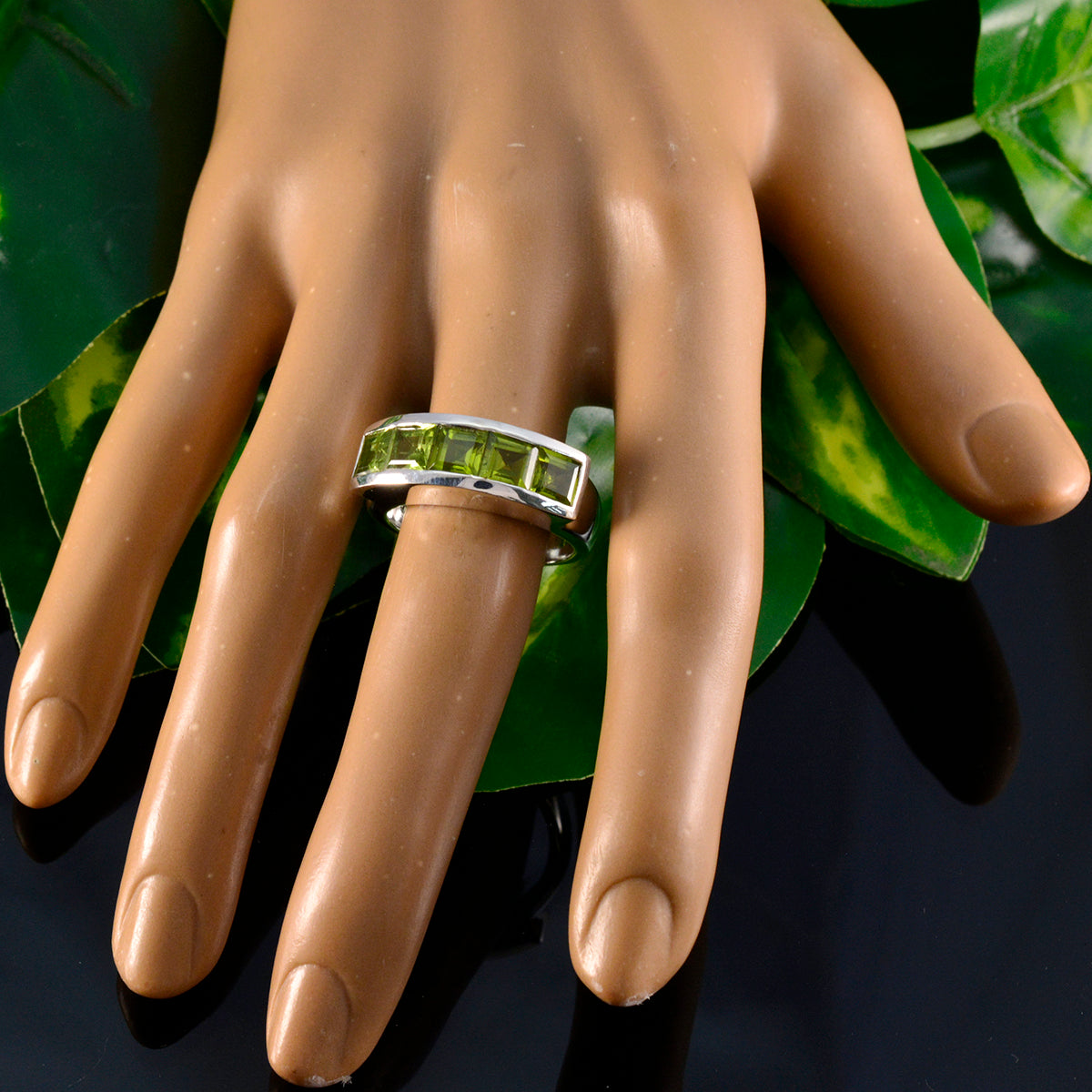 Rebeca silver band with rectangular peridot stones on mannequin hand green gemstone contemporary ring ideal for everyday wear