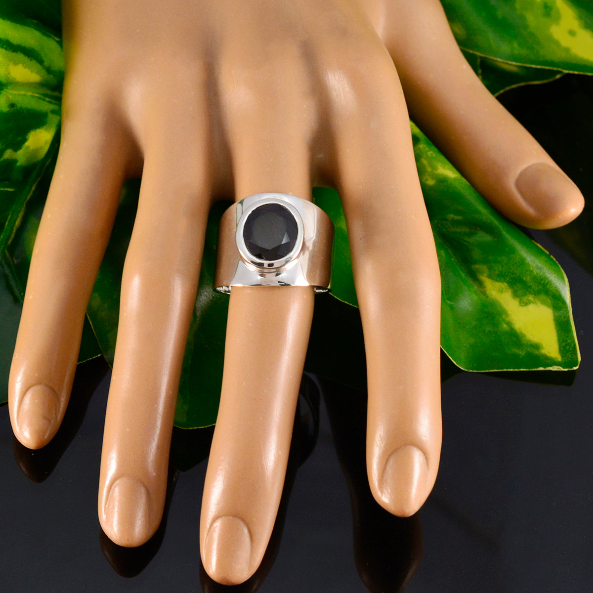 Camilla blue solitaire statement ring with a large dark blue stone on silver band showcased on mannequin hand