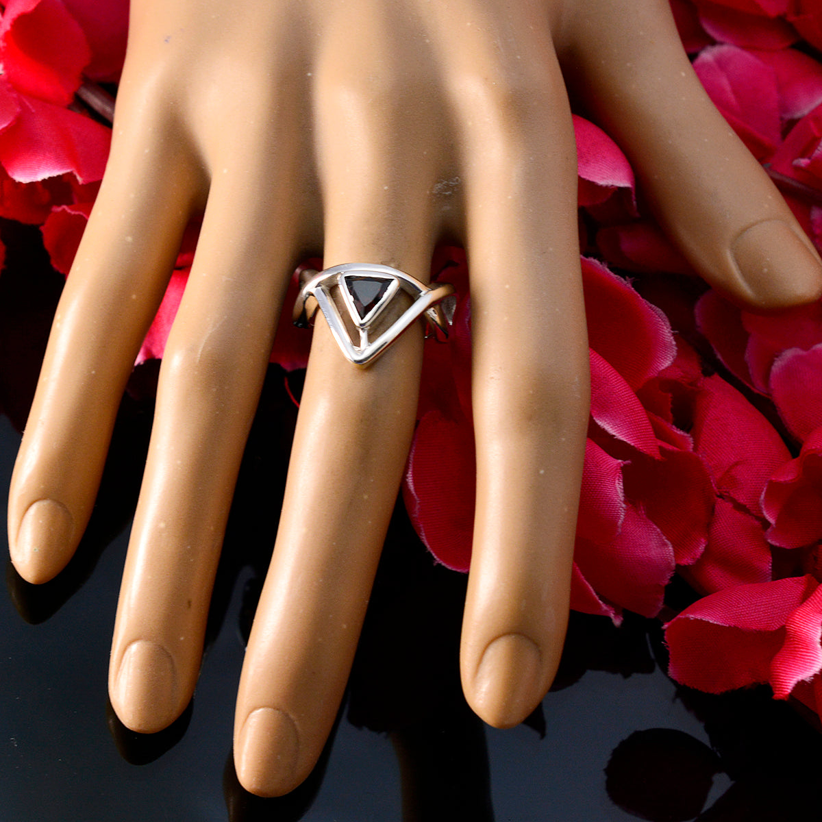 Maria geometric red solitaire ring with silver triangular design on mannequin hand with red petals